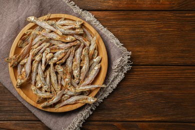 Tasty dried anchovies on wooden table, top view. Space for text