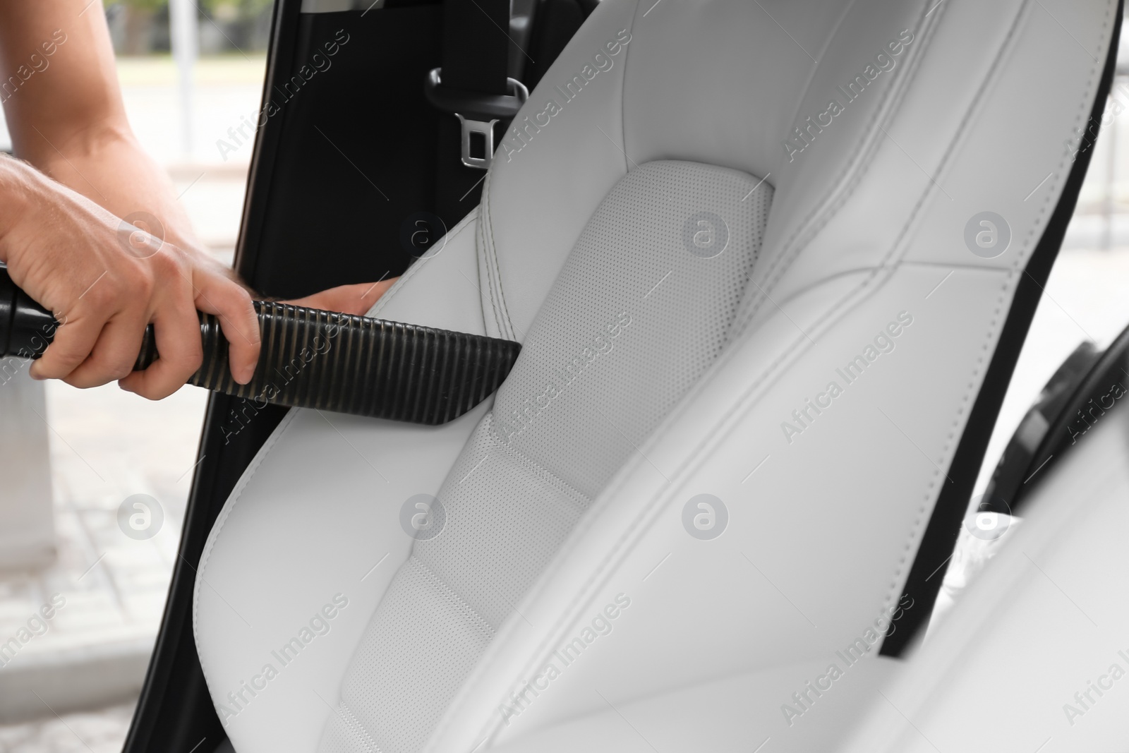 Photo of Man using vacuum cleaner in auto, closeup. Car wash