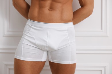 Photo of Young man in stylish underwear near white wall, closeup