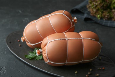 Tasty boiled sausages on dark textured table, closeup