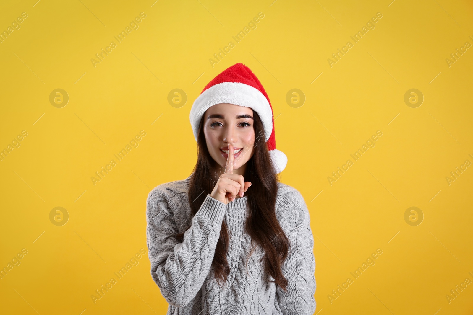 Photo of Beautiful woman wearing Santa Claus hat on yellow background