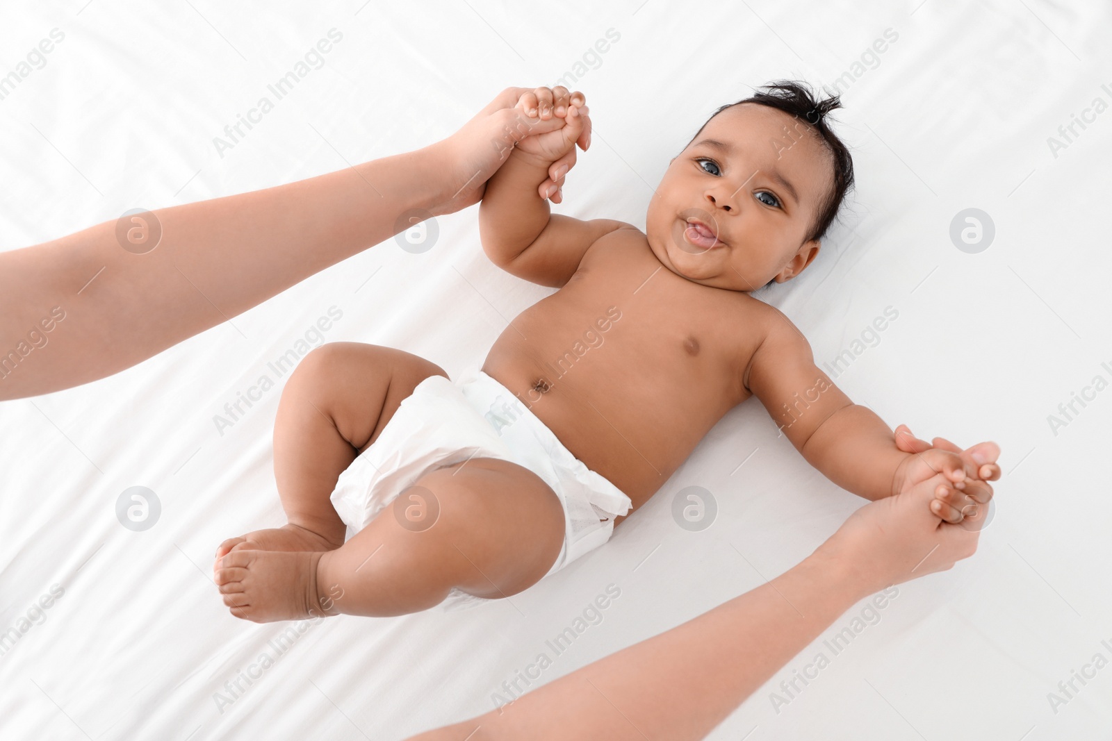 Photo of Mother and her cute child on white bed, above view. Baby massage and exercises