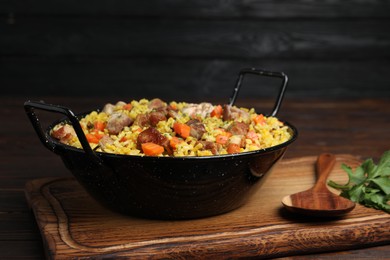 Photo of Delicious pilaf with meat and carrot served on wooden board