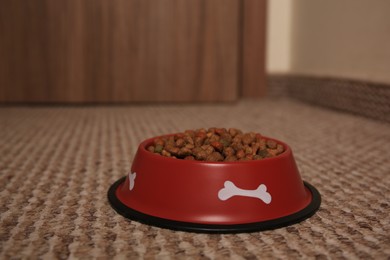 Dry dog food in feeding bowl on soft carpet indoors