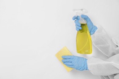 Photo of Woman in protective suit cleaning mold with sprayer and rag on wall, closeup. Space for text