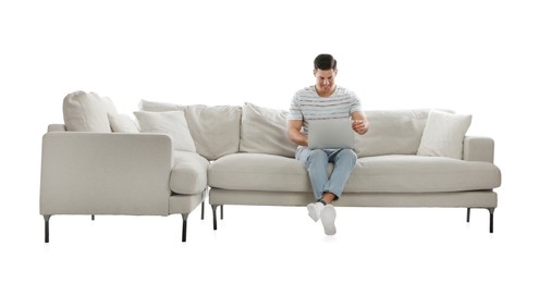 Man with laptop on comfortable sofa against white background