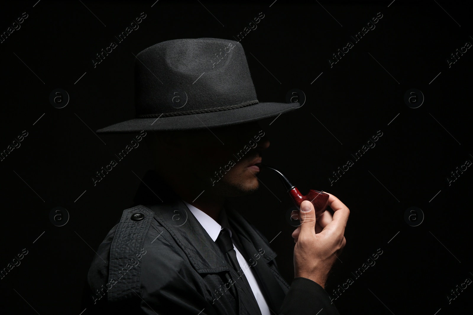 Photo of Old fashioned detective with smoking pipe on dark background