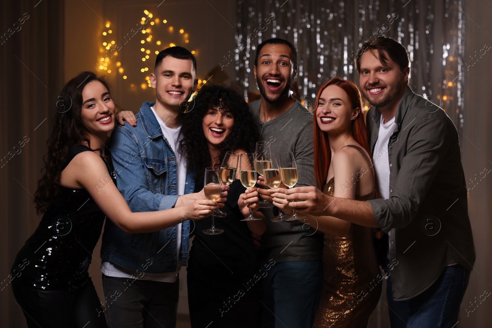 Photo of Happy friends with glasses of sparkling wine celebrating birthday indoors