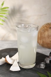 Photo of Glass of coconut water, ice cubes and nuts on table