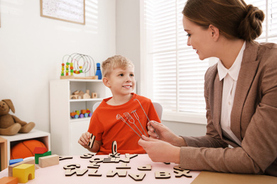 Speech therapist using logopedic probes during session with little boy in office