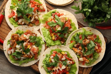 Photo of Delicious tacos with vegetables and meat on wooden table, flat lay