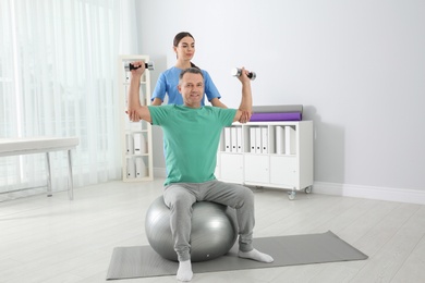 Photo of Doctor working with patient in hospital. Rehabilitation exercises