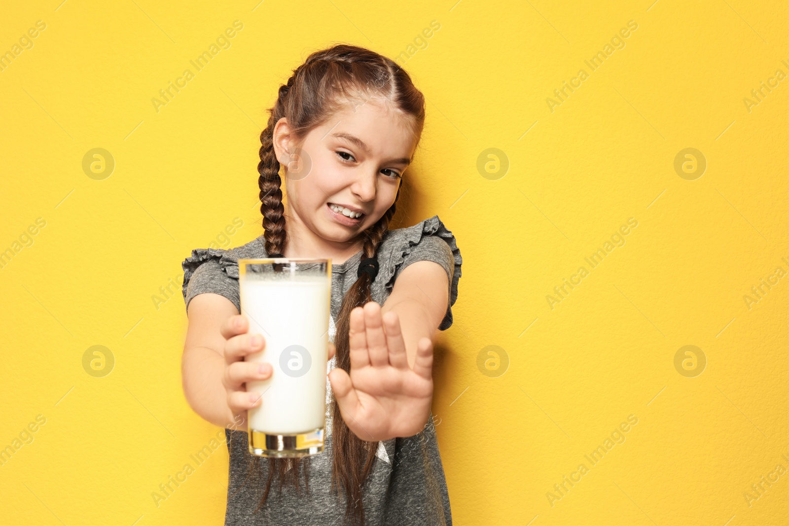 Photo of Little girl with dairy allergy holding glass of milk on color background