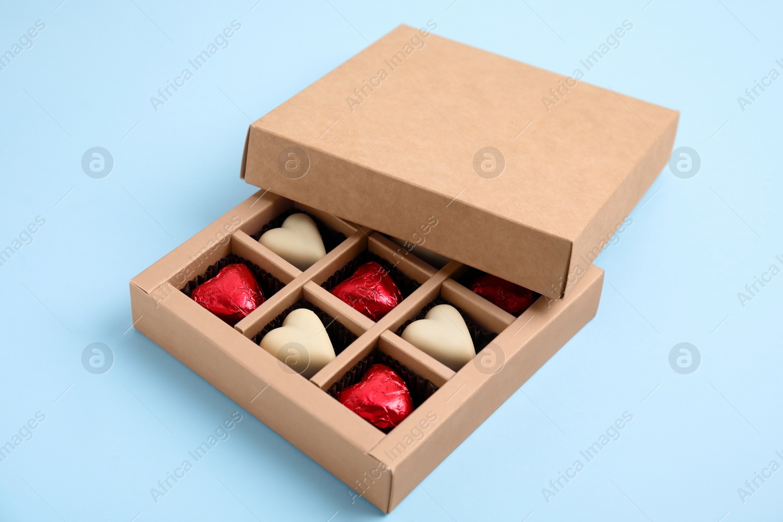 Photo of Tasty heart shaped chocolate candies on light blue background. Happy Valentine's day