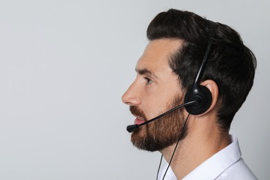 Photo of Hotline operator with headset on light grey background, space for text