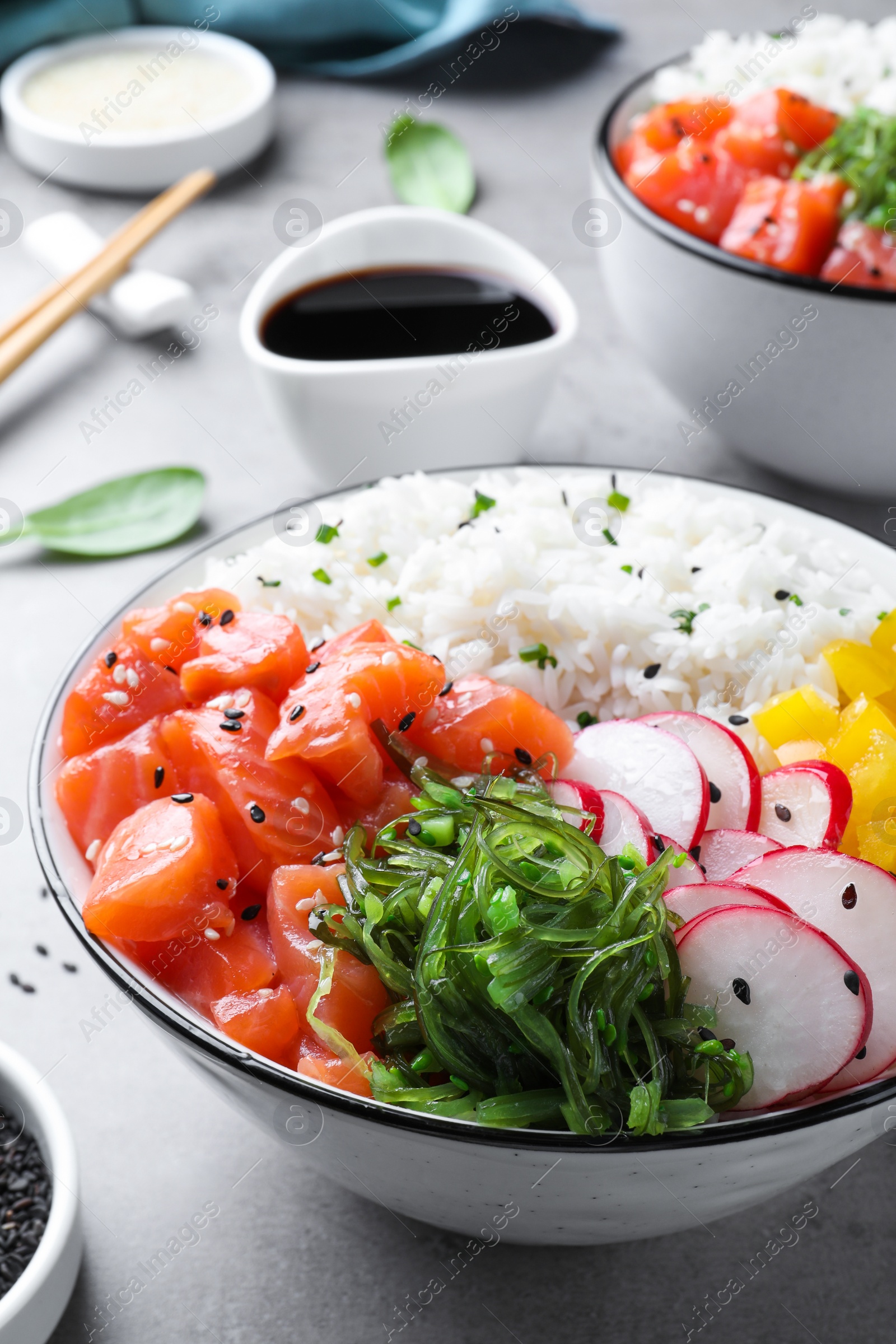 Photo of Delicious poke bowl with salmon and vegetables served on light grey table