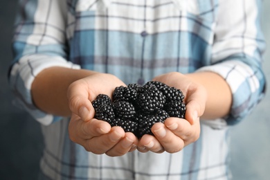 Photo of Young woman with handful of ripe blackberries, closeup