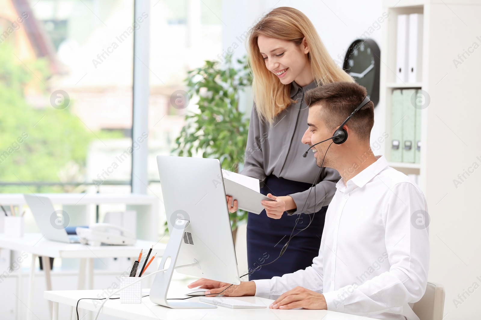 Photo of Young female receptionist with trainee at workplace