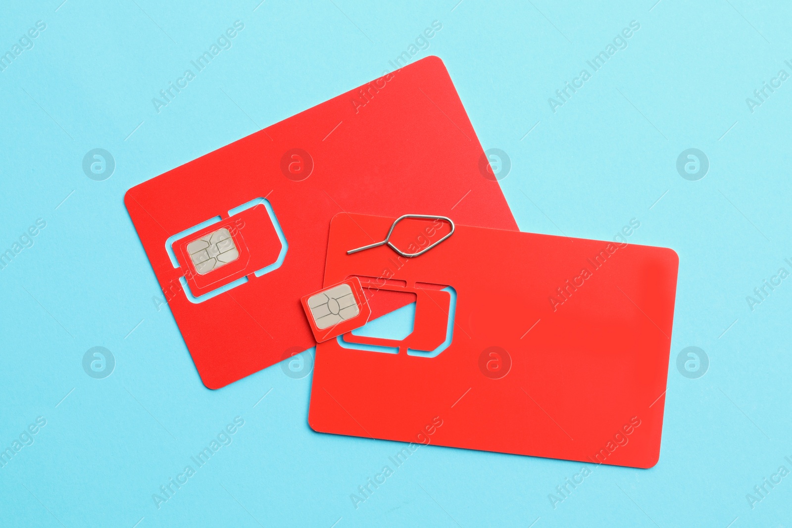 Photo of Red SIM cards on light blue background, flat lay