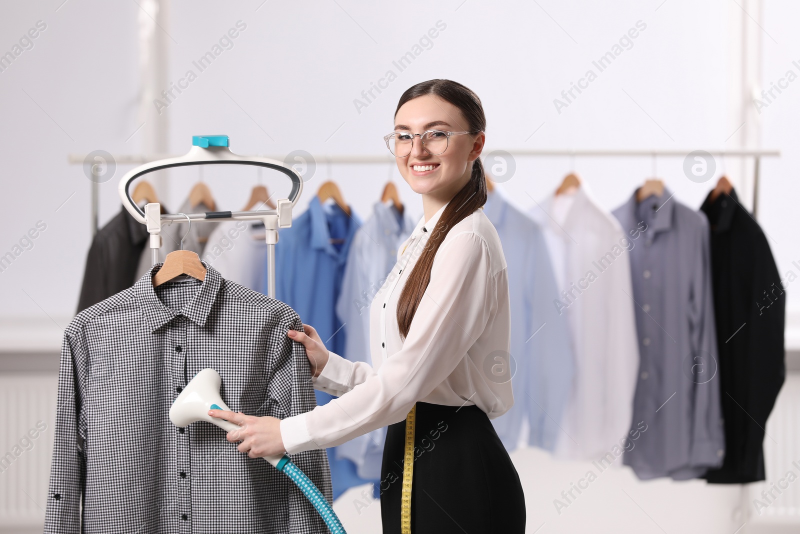 Photo of Woman steaming shirt on hanger in room