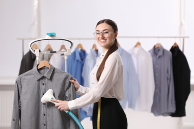 Woman steaming shirt on hanger in room