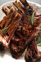 Photo of Delicious grilled ribs with rosemary in plate, closeup