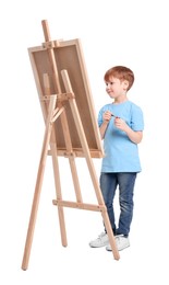 Little boy painting against white background. Using easel to hold canvas