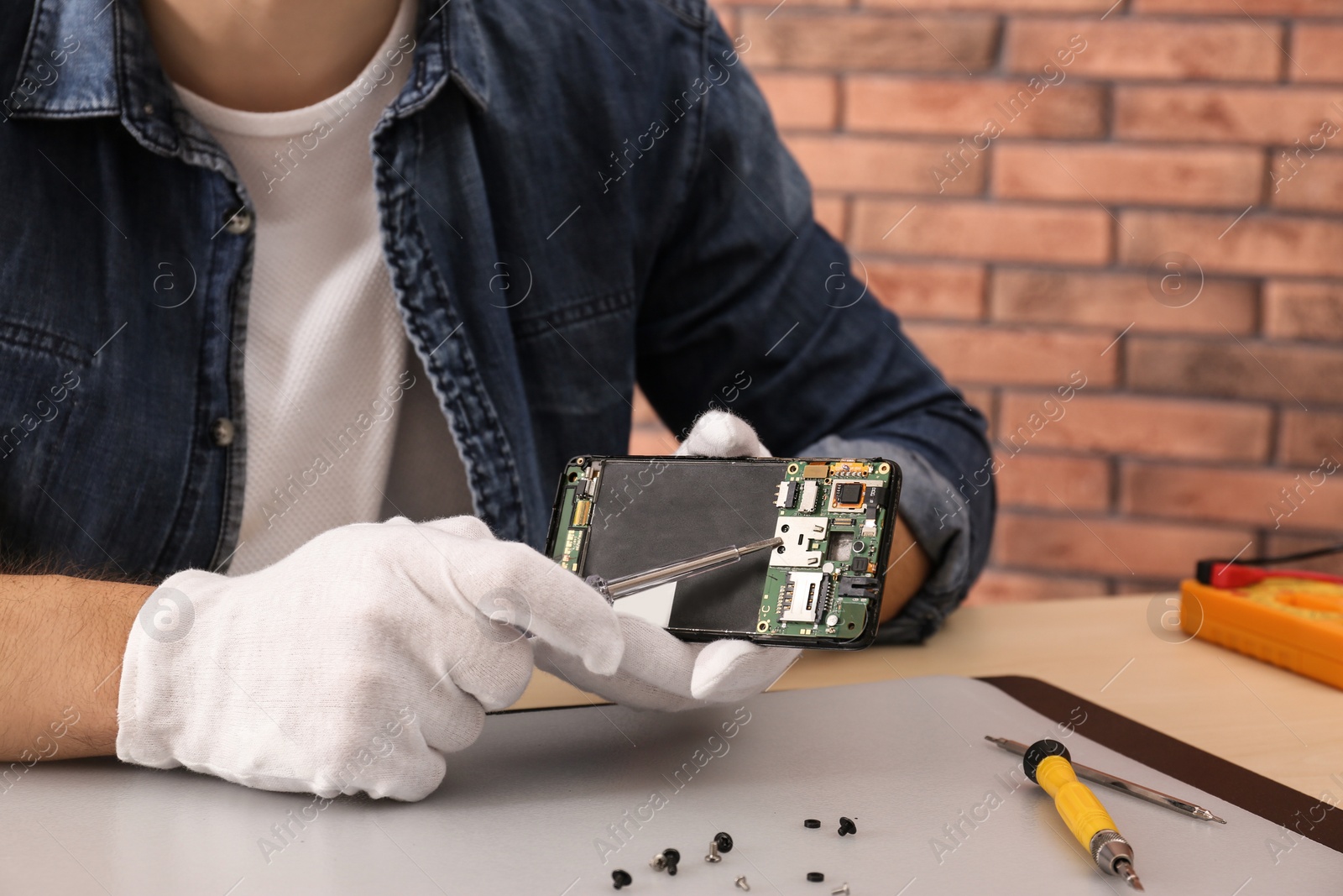 Photo of Technician repairing broken smartphone at table, closeup. Space for text