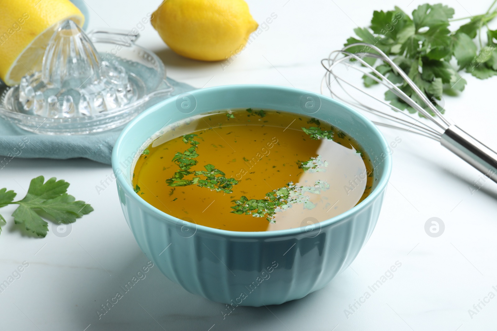 Photo of Bowl with lemon sauce on white table. Delicious salad dressing