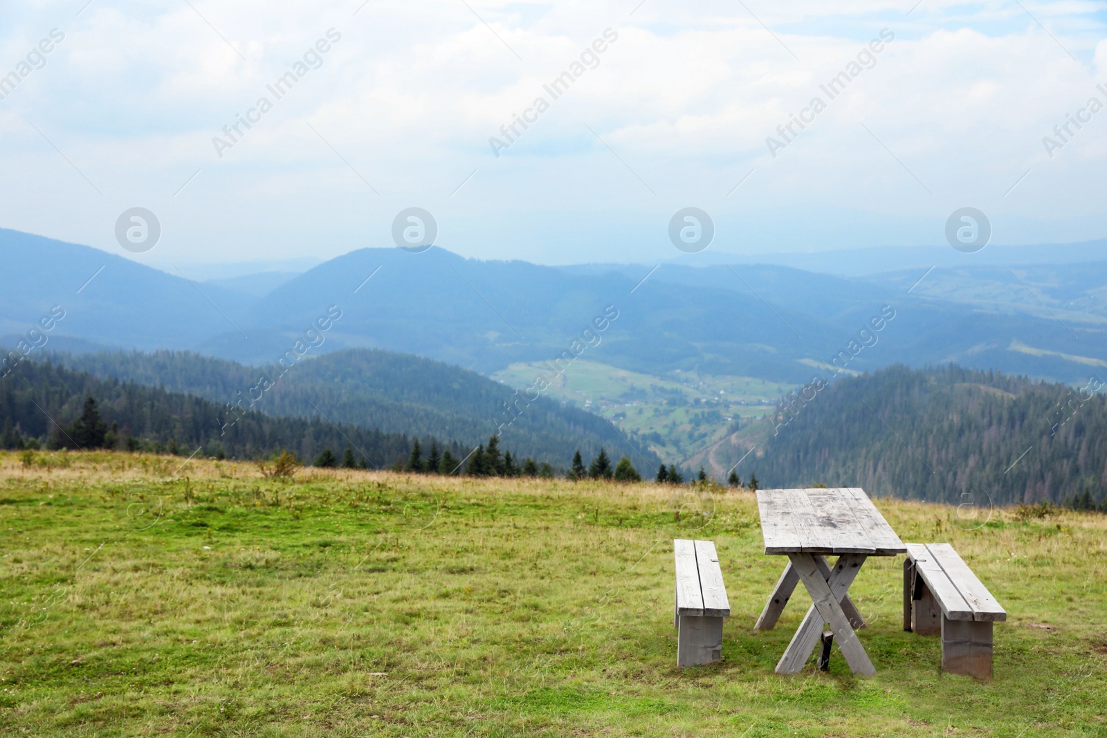 Photo of Picturesque landscape with wooden picnic table and mountain forest on background