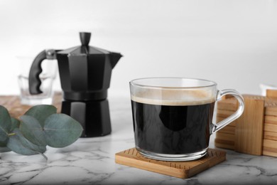 Mug of hot drink and stylish cup coasters in holder on marble table