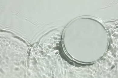 Photo of Stylish presentation for product. Glass podium in water on white background, top view. Space for text