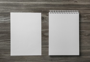 Photo of Sheet of paper and blank brochure on wooden table, flat lay. Mockup for design