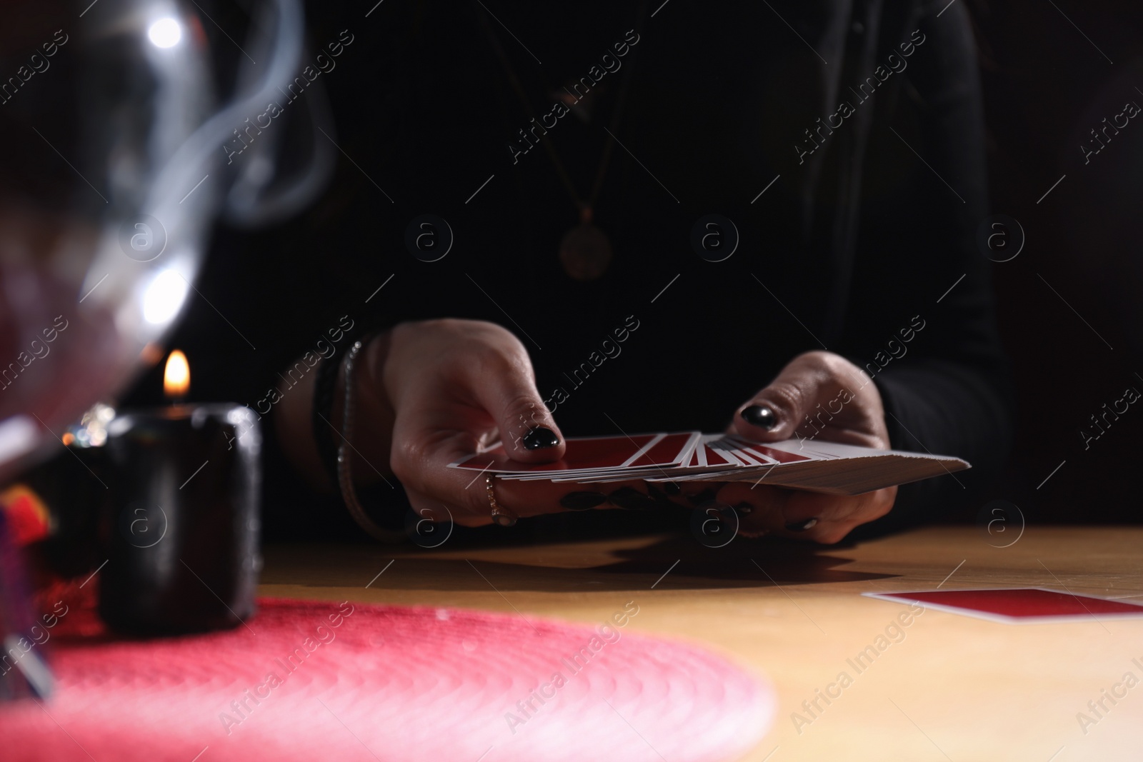 Photo of Soothsayer predicting future with cards at table indoors, closeup