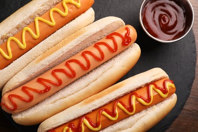 Photo of Delicious hot dogs with sauces and French fries on wooden table, top view