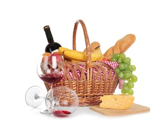 Photo of Picnic basket with food and glasses of wine on white background