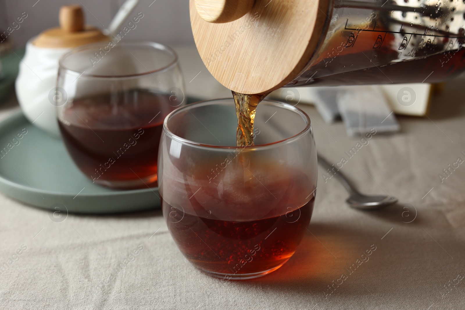 Photo of Pouring warm tea into cup on light table, closeup