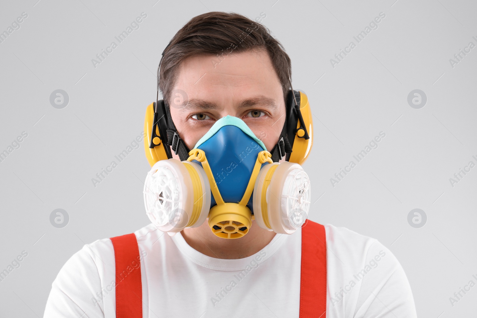 Photo of Male industrial worker in uniform on light background. Safety equipment