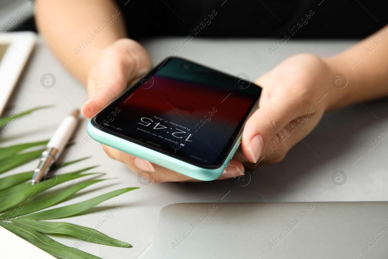 Photo of MYKOLAIV, UKRAINE - JULY 9, 2020: Woman holding Iphone 11 with lock screen at table, closeup