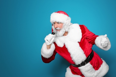 Photo of Santa Claus singing into microphone on color background. Christmas music