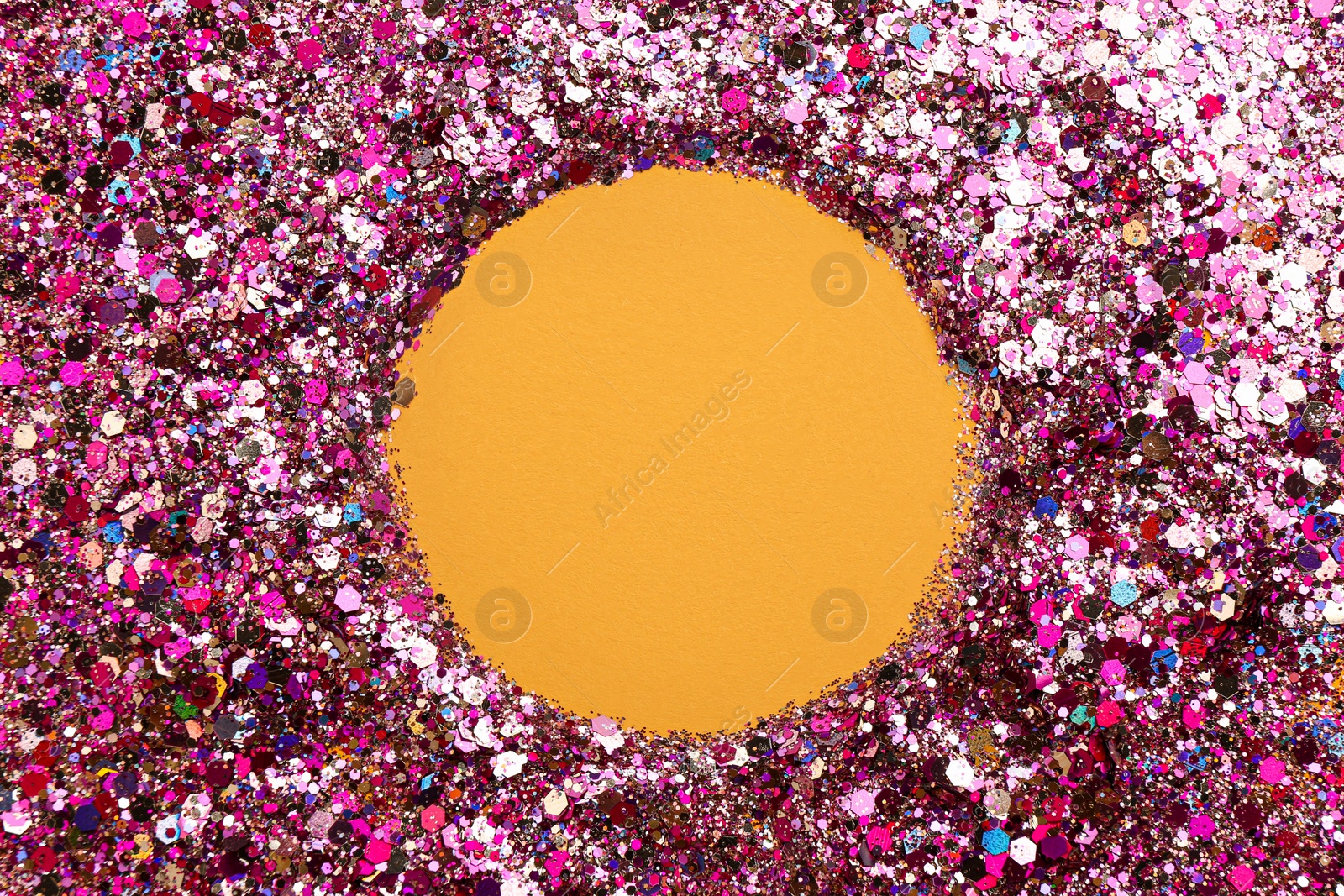 Photo of Frame of shiny bright pink glitter on yellow background, flat lay. Space for text