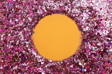 Photo of Frame of shiny bright pink glitter on yellow background, flat lay. Space for text