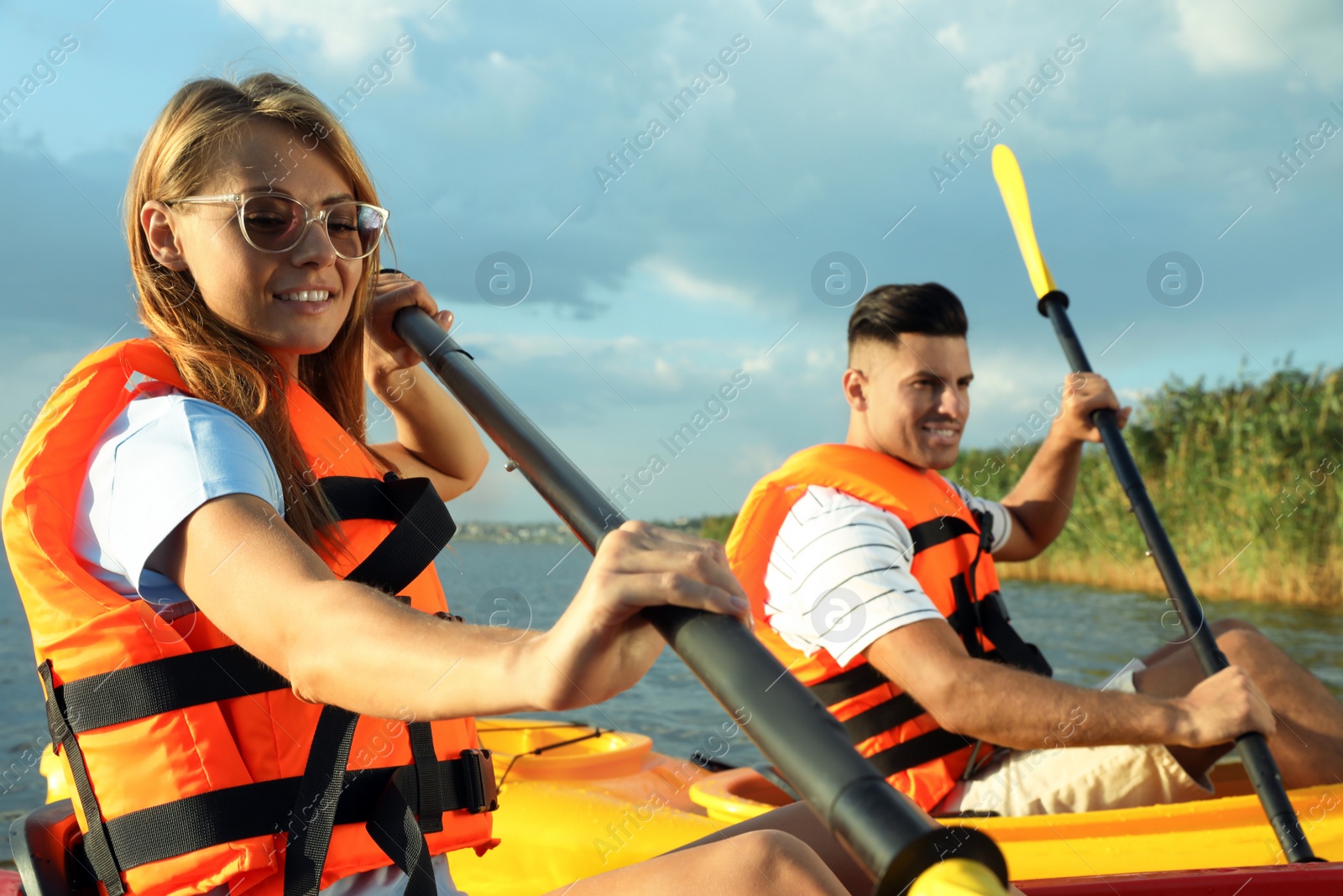 Photo of Couple in life jackets kayaking on river. Summer activity