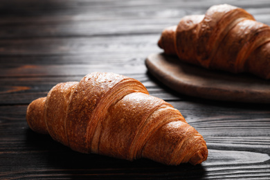 Photo of Tasty fresh crispy croissants on wooden table