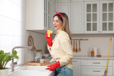 Photo of Woman singing while washing dishes in kitchen