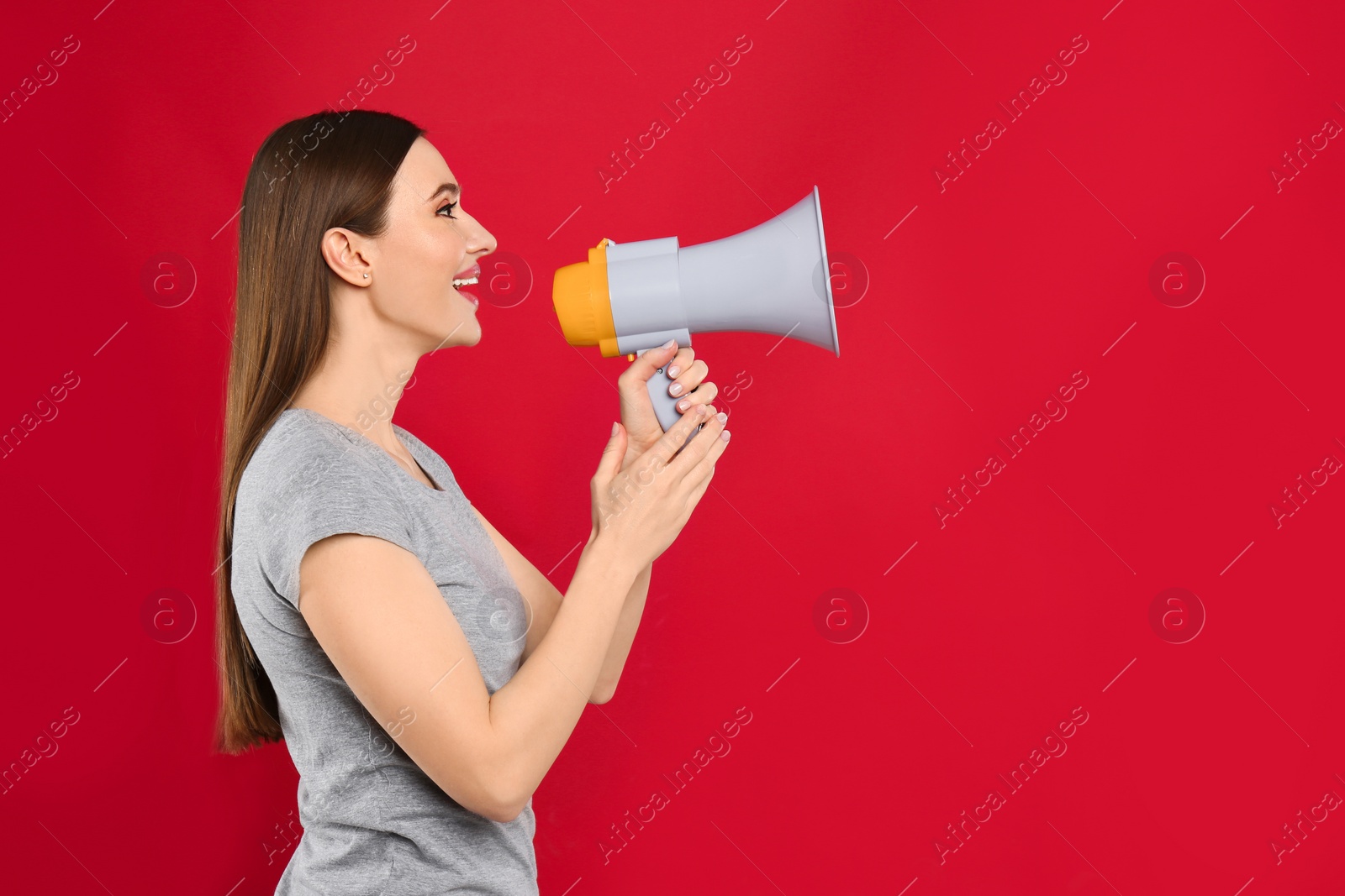 Photo of Young woman with megaphone on red background. Space for text