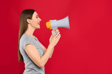 Young woman with megaphone on red background. Space for text