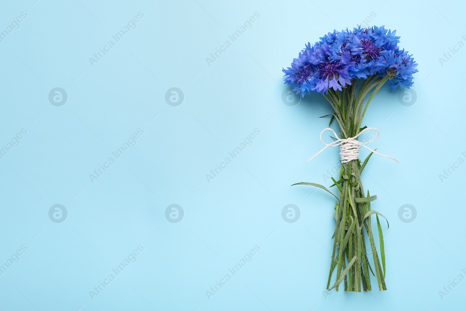 Photo of Bouquet of beautiful cornflowers on turquoise background, top view. Space for text