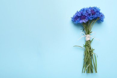 Photo of Bouquet of beautiful cornflowers on turquoise background, top view. Space for text