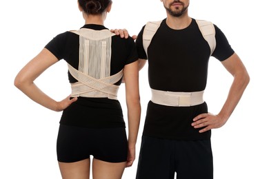 Photo of Closeup view of man and woman with orthopedic corsets on white background